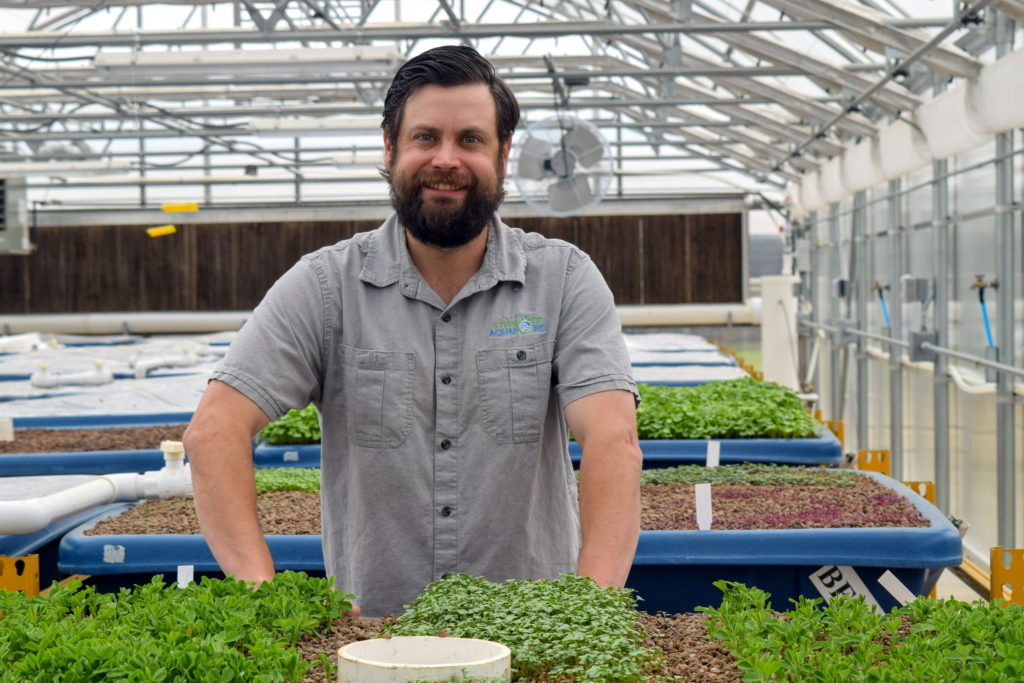 1-kaben-smallwood-stands-behind-a-growbed-full-of-herbs-at-the-eastern-oklahoma-state-college-aquaponic-greenhouse-in-wilburton-oklahoma